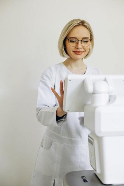 Oftalmologista de mulher ao lado do equipamento de optometria