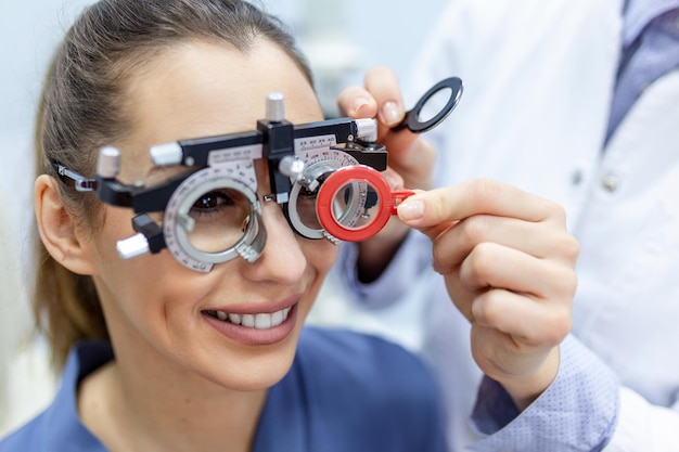 Oftalmologista examinando mulher com paciente do sexo feminino com quadro de teste optometrista para verificar a visão na clínica oftalmológica