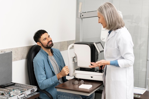 Oftalmologista explicando o funcionamento do autorefractor a um paciente em uma clínica oftalmológica