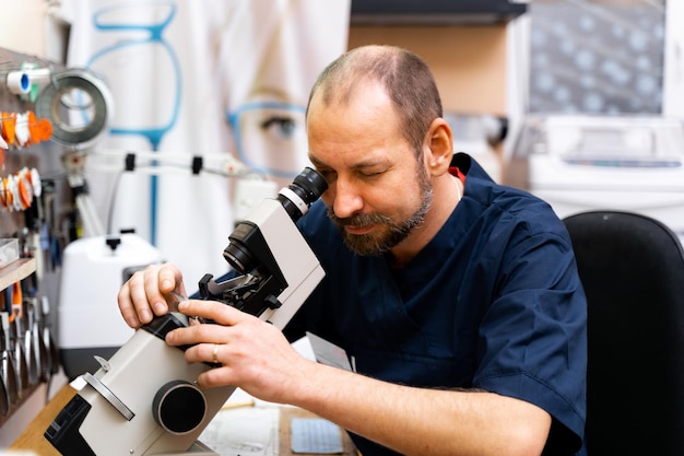 Oftalmólogo produce lentes personalizados para anteojos Hombre trabaja con microscopio