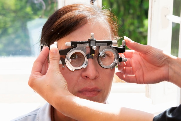 Un oftalmólogo selecciona anteojos para una mujer con un juego de lentes de anteojos de prueba