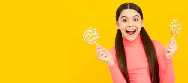 Oh, Dios mío, chico genial con el pelo largo, sostenga piruletas de caramelo en la tienda de dulces de caramelo de palo. Niño adolescente con dulces.