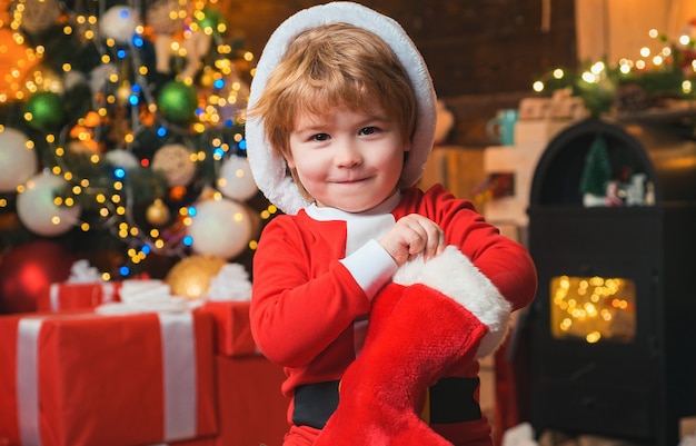 Oh glücklicher Tag. Das fröhliche Gesicht des Kindes bekam Geschenk in der Weihnachtssocke.