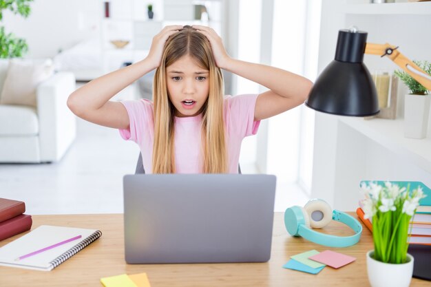 Oh no, no apruebo mi examen semestral. Niño frustrado niña sentarse mesa escritorio estudio uso remoto portátil molesto por los resultados de su examen tocar la cabeza de las manos en casa en el interior