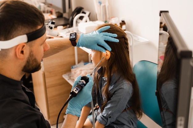 Ohren-Endoskopie des Kindes Otoskopie-Verfahren mit Otoskop HNO-Arzt HNO-Arzt behandeln Ohren des Mädchens
