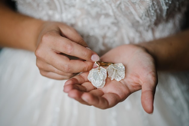 Ohrring in weiblichen Händen auf weißem Hintergrund Hochzeit stilvolles Accessoire Braut Elegante Braut mit silbernen Ohrringen Hände mit Schmuck Nahaufnahme