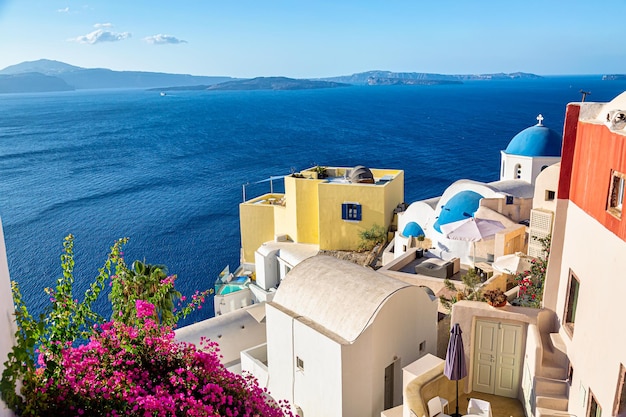Oia-Dorf mit berühmten weißen Häusern Bougainvillea-Blume und blauen Kuppelkirchen auf Santorini-Insel Ägäisches Meer Griechenland
