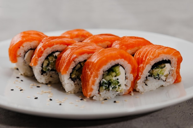 Oito porções de sushi com salmão e pepino em um prato branco.