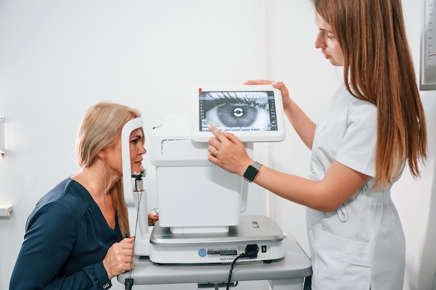 El ojo está en el monitor La vista de la mujer es probada por un trabajador de la clínica que usa un dispositivo especial