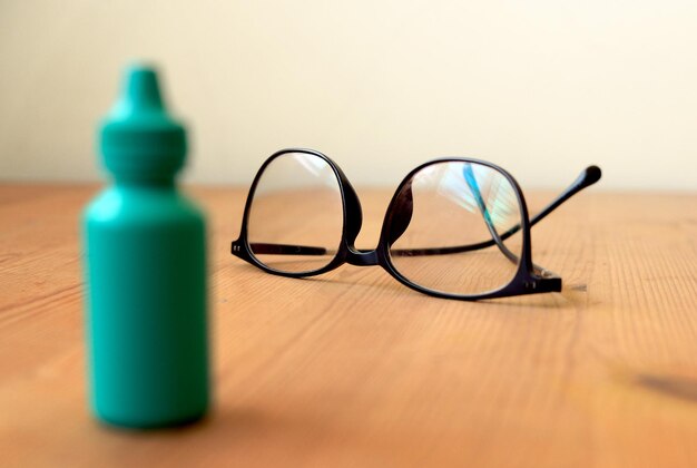 Foto ojo gafas en una mesa de madera con un recipiente de plástico borroso en primer plano