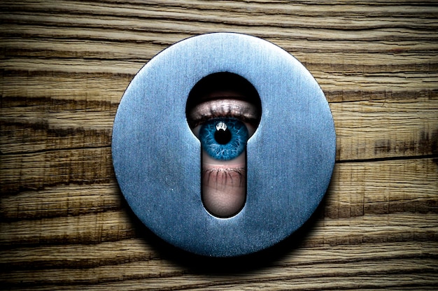 Foto el ojo mira a través del ojo de la cerradura en detalle.