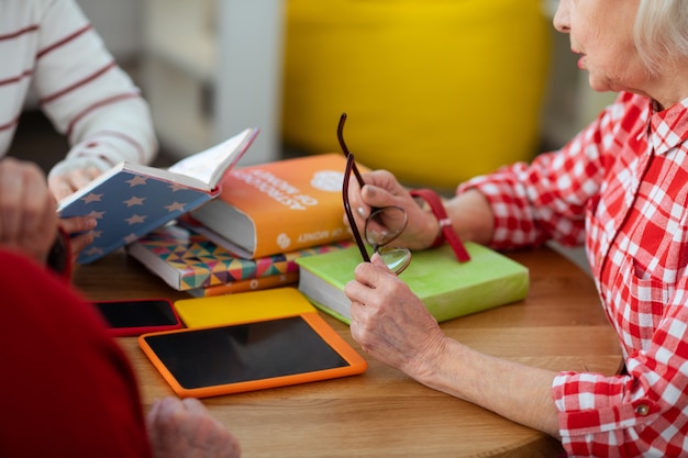 Para los ojos. Cerca de anteojos en manos femeninas durante la discusión sobre libros