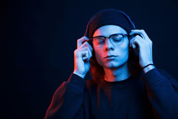 Con los ojos cerrados. Foto de estudio en estudio oscuro con luz de neón. Retrato de hombre serio.