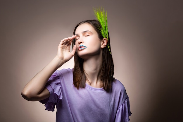 Ojos cerrados. Tierna y atractiva modelo de cabello oscuro que cierra los ojos mientras posa con una espiguilla verde