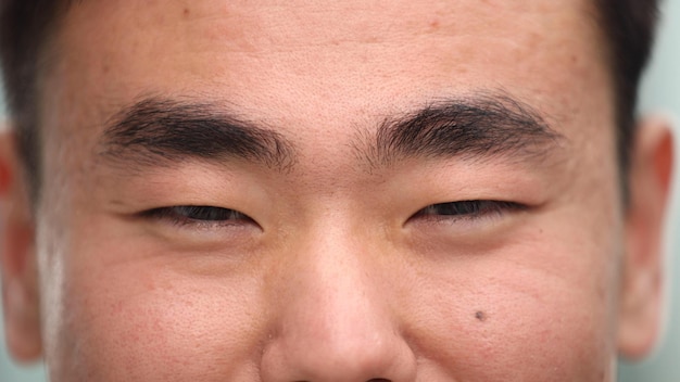 Ojos de un joven asiático feliz mirando a la lente de la cámara