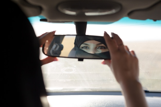 Ojos de mujer musulmana en el espejo retrovisor de un coche.