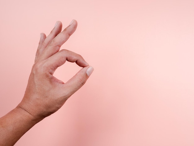 Ok, gesto de sinal de mão por homem adulto isolado em fundo rosa pastel com espaço de cópia. ok, acordo com o gesto dos dedos do homem de meia-idade.