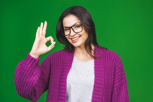 Foto ok signo suéter acogedor alegre hermosa joven vistiendo invierno acogedor aislado sobre fondo verde.