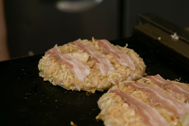 Okonomiyaki es un salado panqueque japonés de repollo a la parrilla como te guste con tu elección de proteínas