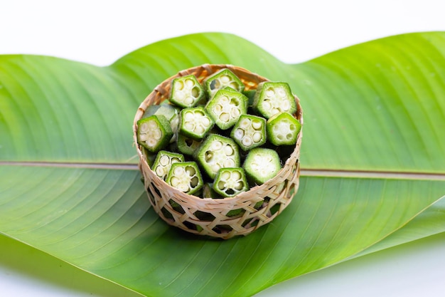 Okra fresca en hoja verde sobre fondo blanco