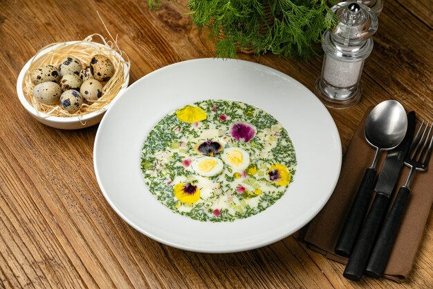 Okroshka com rabanetes verdes ovos cozidos em uma mesa de madeira