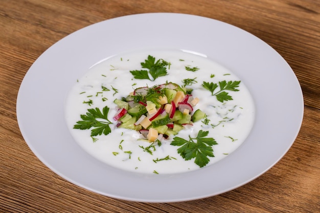 Okroshka Sopa de verduras fría ligera de verano con huevos de pepino, rábano y eneldo en una mesa de madera Un plato tradicional de la cocina rusa o ucraniana Cerrar