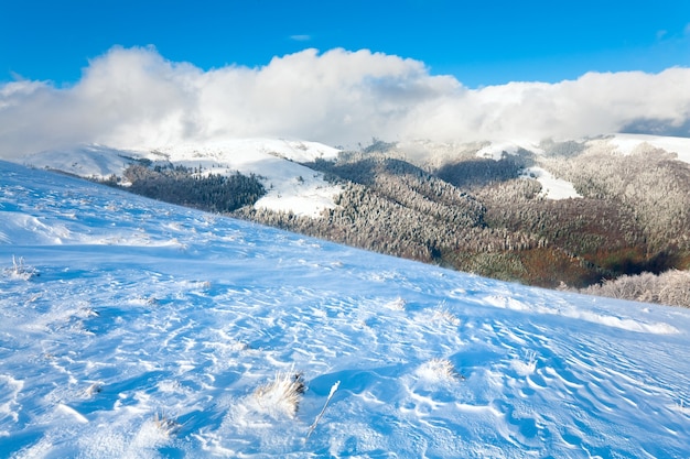 Oktober-Bergblick mit erstem Winterschnee und buntem Laub im letzten Herbst am weiten Berghang