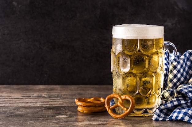 Oktoberfest cerveza y pretzel en mesa de madera.