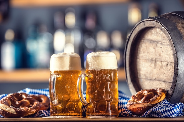 Oktoberfest dois cerveja grande com barril de madeira pretzel e toalha de mesa azul.