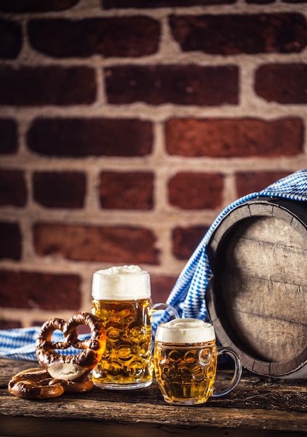 Oktoberfest großes und kleines Bier mit Brezelholzfass und blauer Tischdecke.