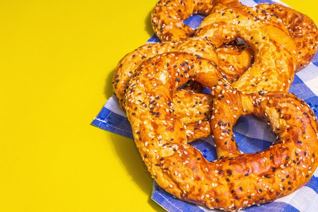 Oktoberfest-Konzept - Brezeln auf einer traditionellen Serviette. Trendiges hartes Licht, dunkler Schatten. Pastellgelber Hintergrund, Platz für Text