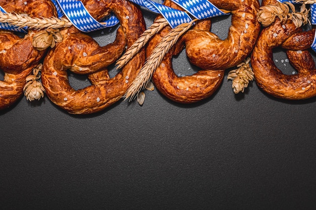 Foto oktoberfest-konzeptbrezeln mit traditionellem musterband und weizenähren