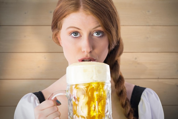 Foto oktoberfest-mädchen trinkt krug bier vor gebleichtem holzbohlenhintergrund