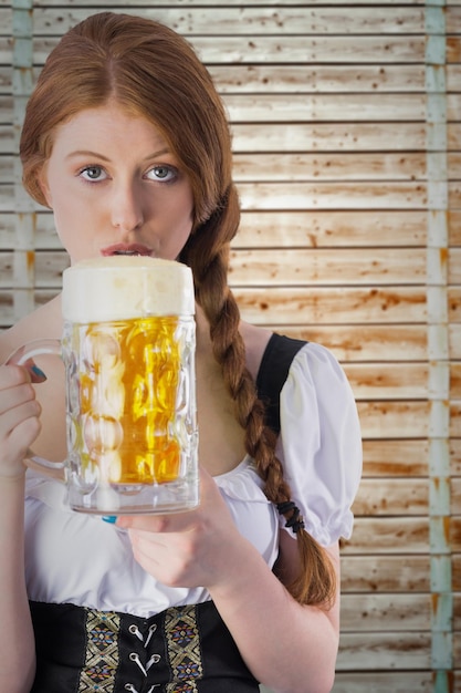 Oktoberfest-Mädchen trinkt Krug Bier vor Holzhintergrund in hellem Holz