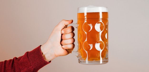 Oktoberfest. Mão de homem com copo de cerveja com espuma. Cerveja gelada fresca no copo na mão. Pub de cerveja.