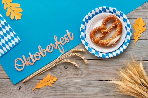 Oktoberfest, plano sobre mesa de madera rústica con pretzels y decoraciones de otoño.