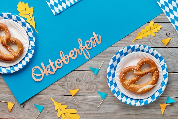 Oktoberfest rustikal mit Prezels in Papptellern, Papierfahnen und Herbstlaub