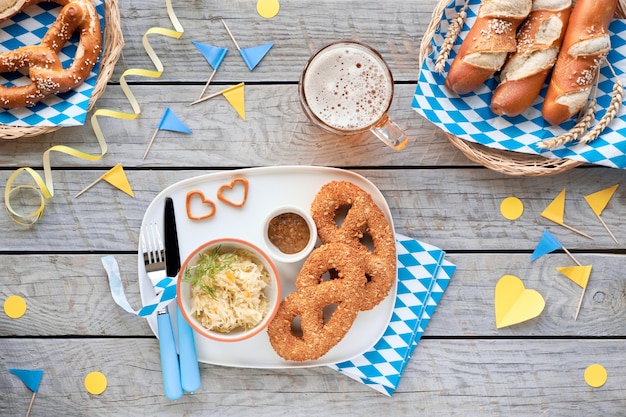 Oktoberfest traditionelles Essen und Bier auf dekoriertem Holztisch. Leberwurst Brezeln mit Sauerkraut, Brot Brezeln und Sticks.