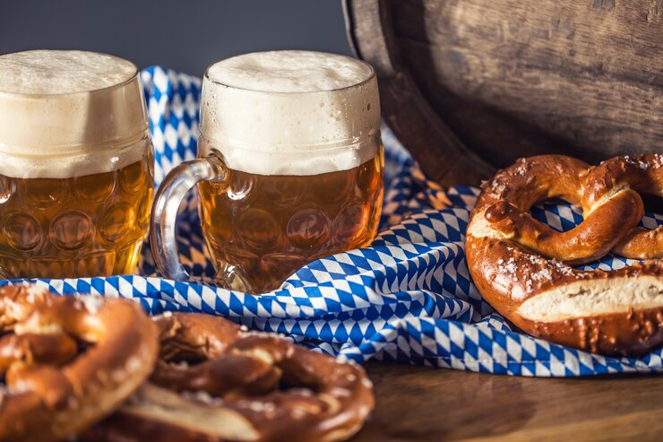 Oktoberfest zwei Bier mit Brezelholzfass und blauer Tischdecke.