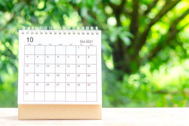 Oktobermonat, Kalendertisch 2021 für Organisatoren zur Planung und Erinnerung auf Holztisch mit grünem Naturhintergrund.