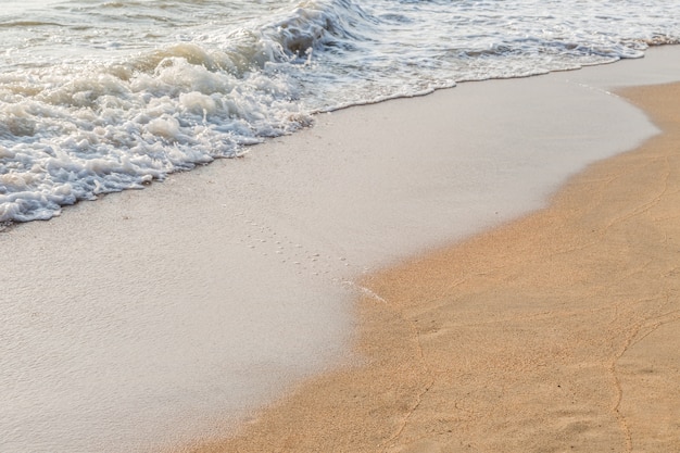 Ola de agua blanca del mar en el fondo de la playa de arena