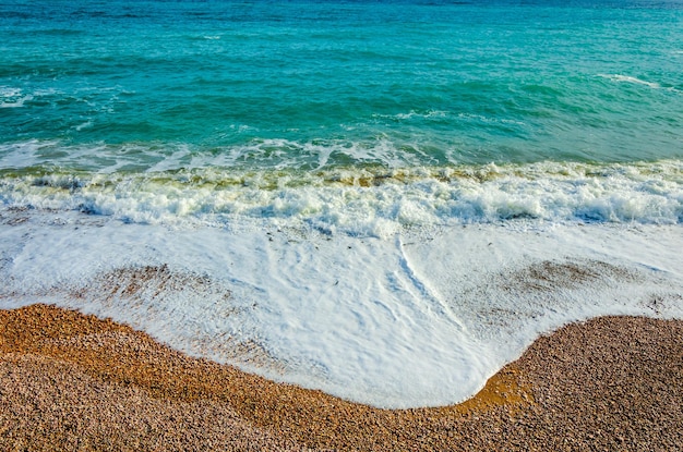 Una ola corre sobre una playa de guijarros.