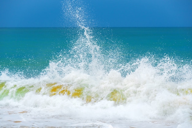 Foto ola de espuma, que se ejecuta en la orilla arenosa.