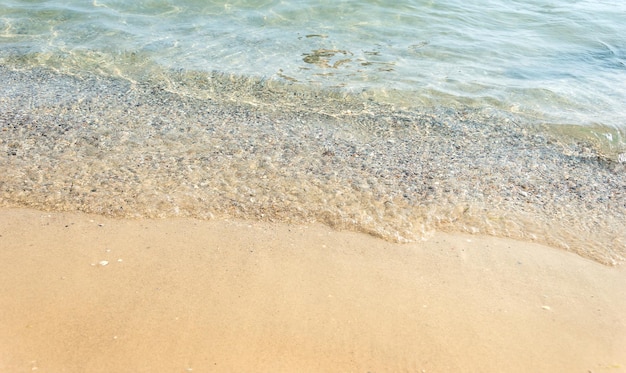 Ola de mar azul en la playa de arena. De cerca