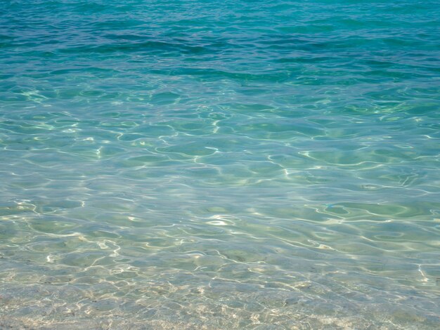 Ola de mar brillante de agua de mar en el fondo de la playa.