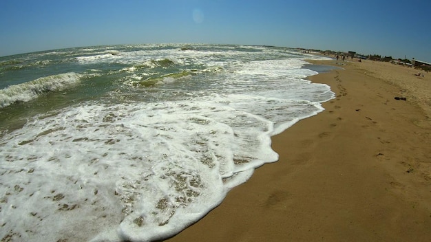 La ola del mar con espuma blanca rueda sobre la orilla arenosa de la vista superior de la playa