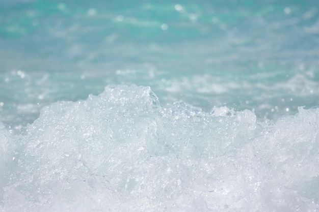 La ola del mar rompe en la orilla y hace que el agua y la espuma aireada blanca salpiquen Foto de alta calidad