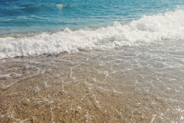 Ola de océano azul en la playa de arena de cerca