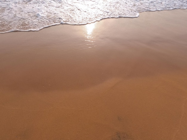 Ola de océano blanco suave en una playa de arena limpia