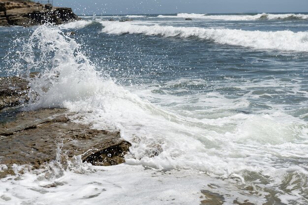 La ola de salpicaduras rueda sobre las rocas del océano